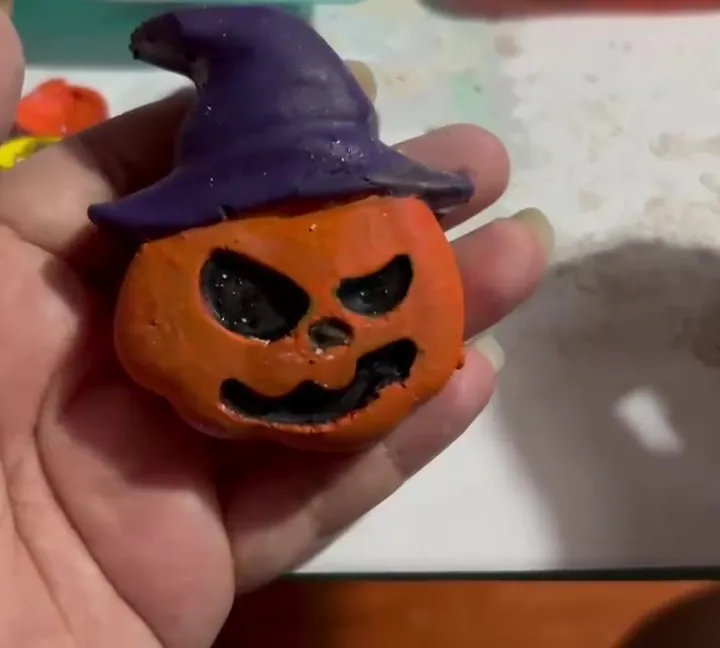 Calabaza de yeso pintada sostenida en la palma de una mano adulta, para mostrar su tamaño